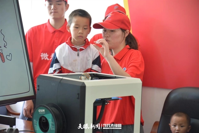 志愿者带领学生参观3D打印机.webp.jpg 志愿者带领学生参观3D打印机.webp.jpg